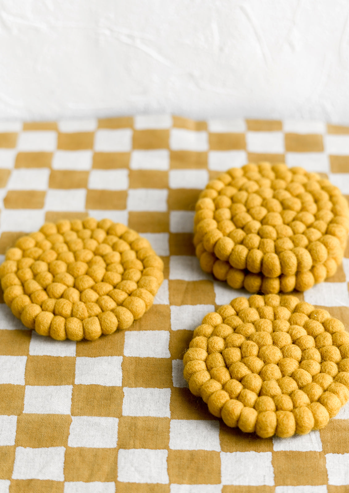 A set of round felted wool coasters in mustard.