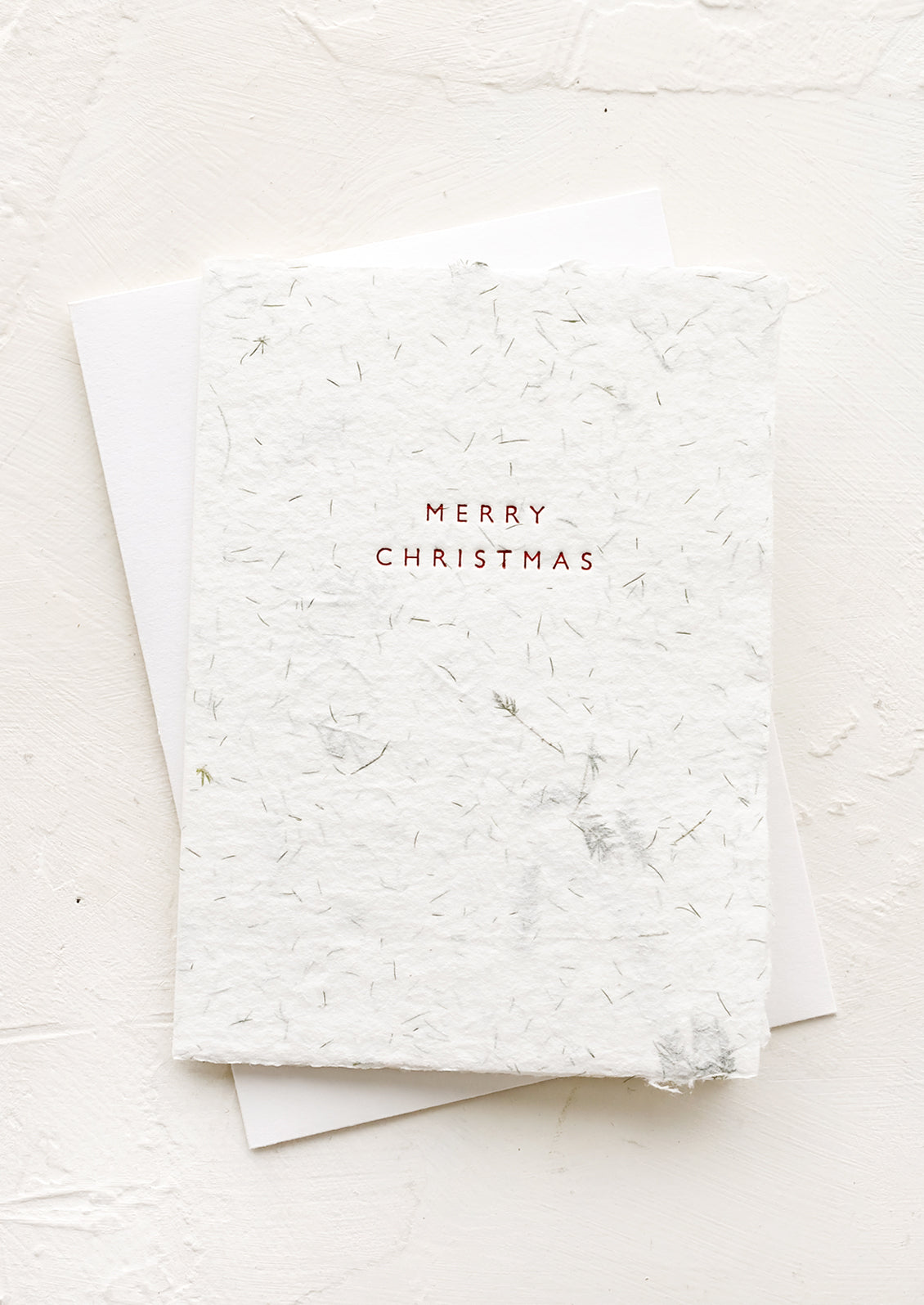 A botanical fern paper folded card reading "merry christmas" in red lettering.