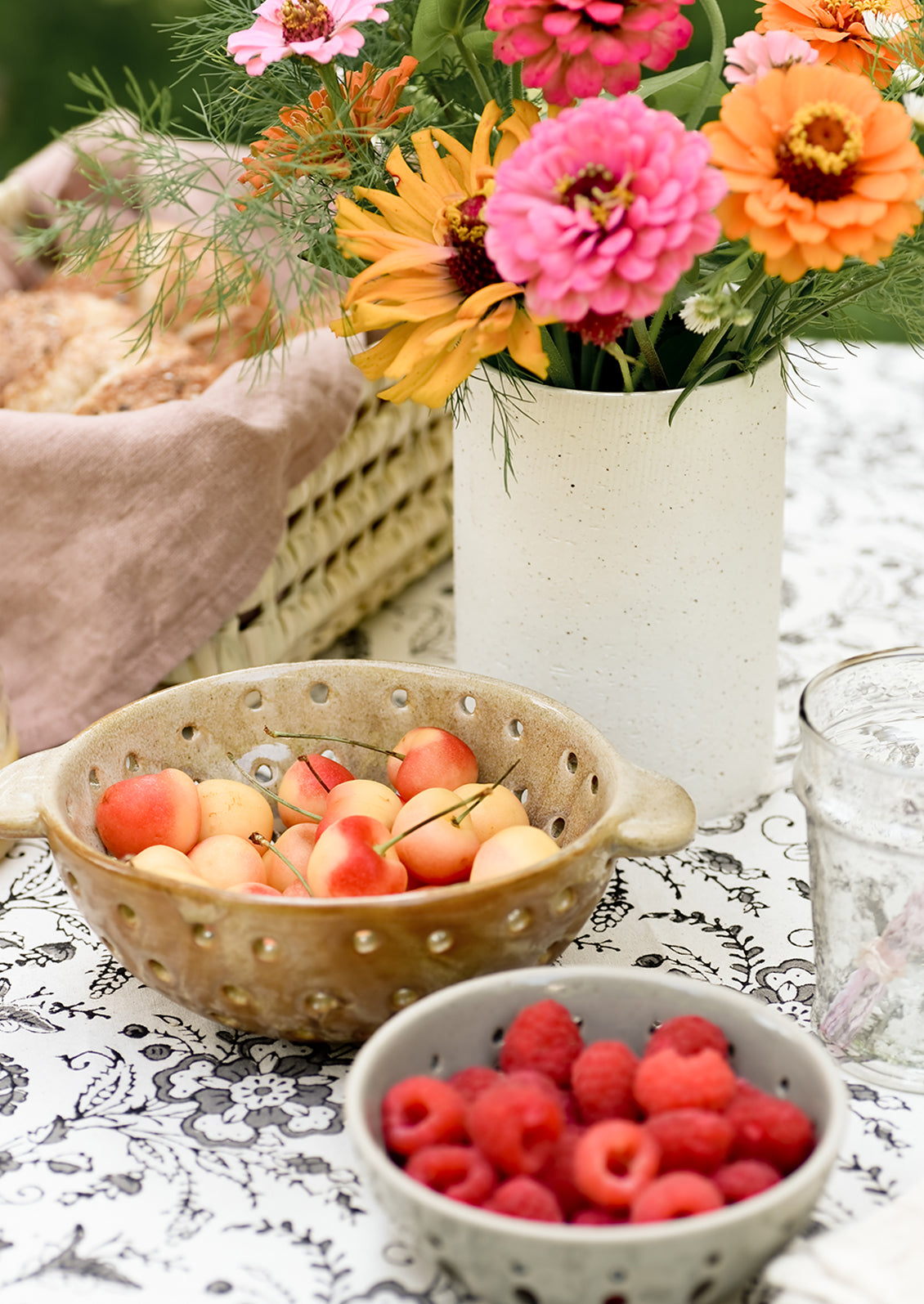 A vase with flowers on table with berry bowls.