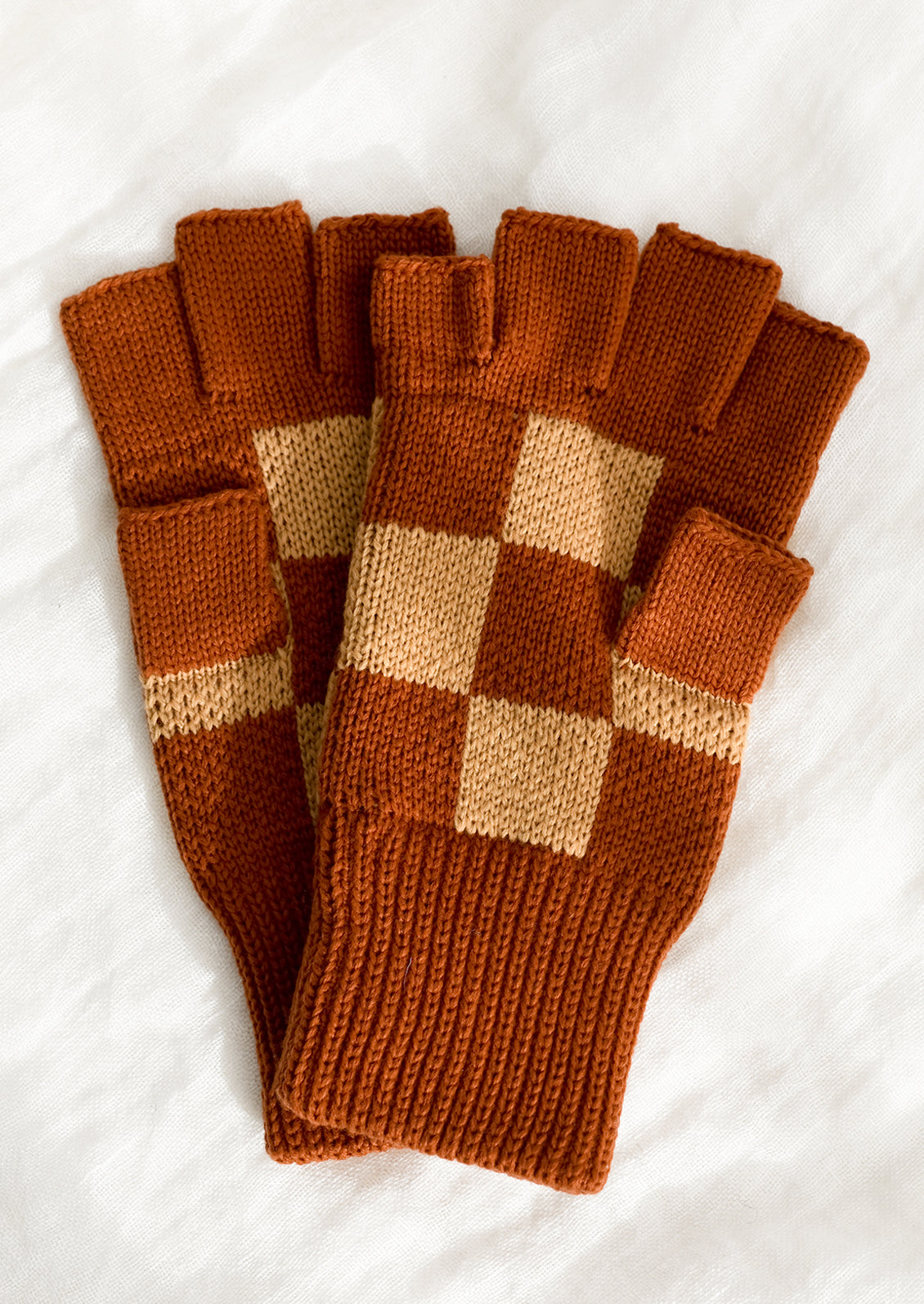 A pair of knit fingerless gloves in terracotta checker.