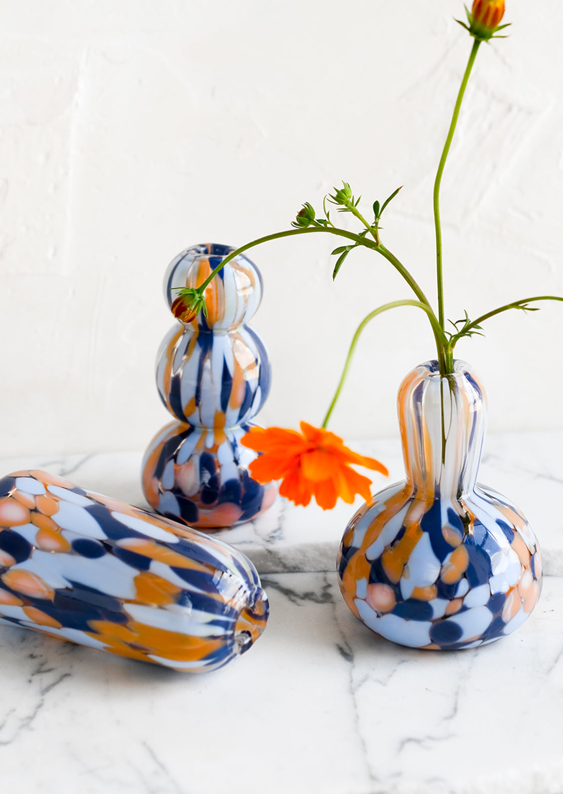 Blue and orange speckle patterned glass vases in assorted shapes.