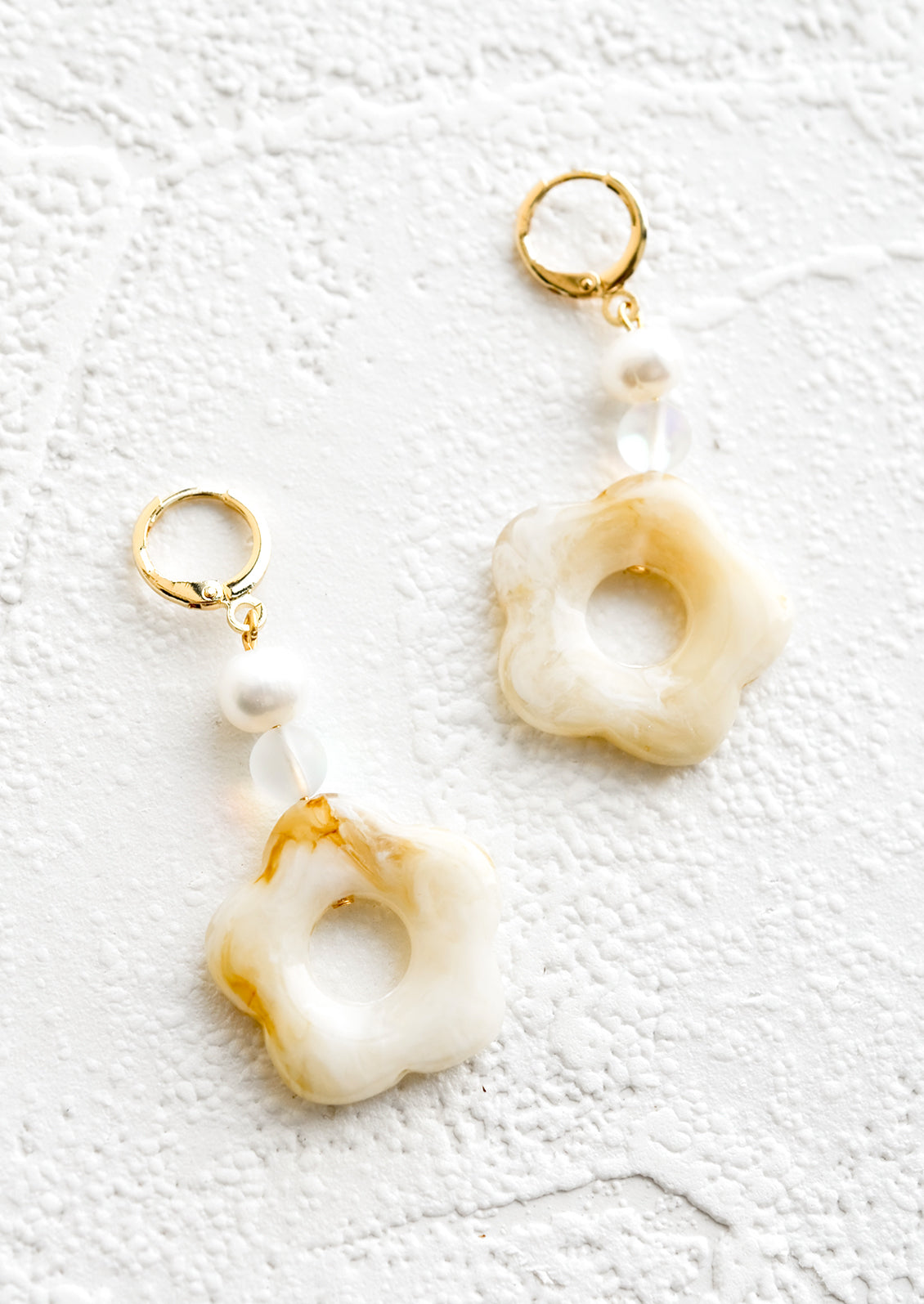 A pair of pearl and tan/white flower beaded dangle earrings strung from a gold huggie hoop.