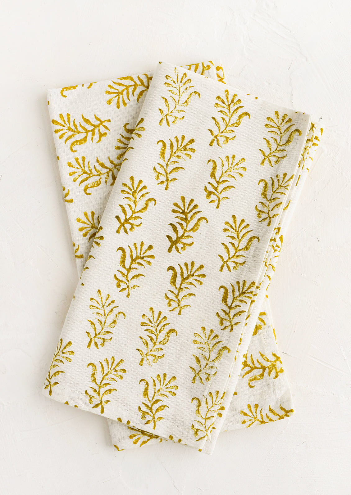 A pair of block printed napkins in white with yellow floral print.