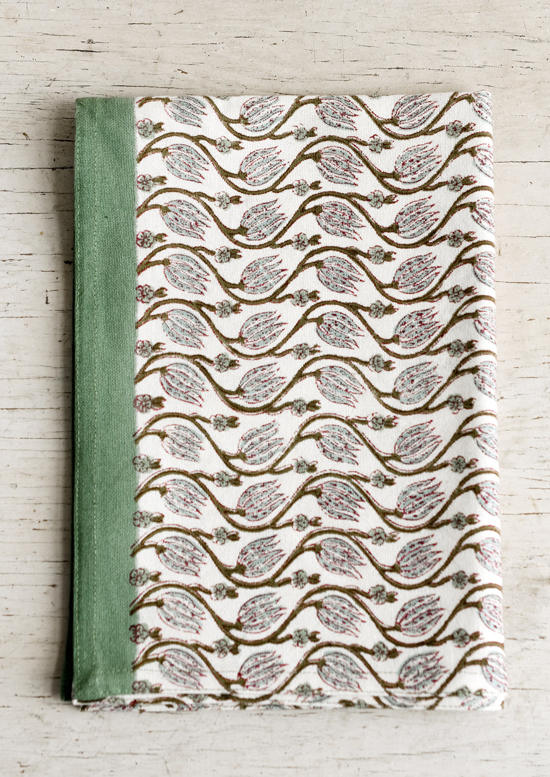 A tea towel with ivy green print and trim.