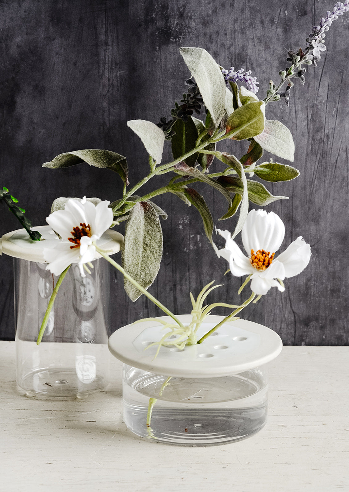 Glass flower frog vases with ceramic lids showing cosmos and lavender.