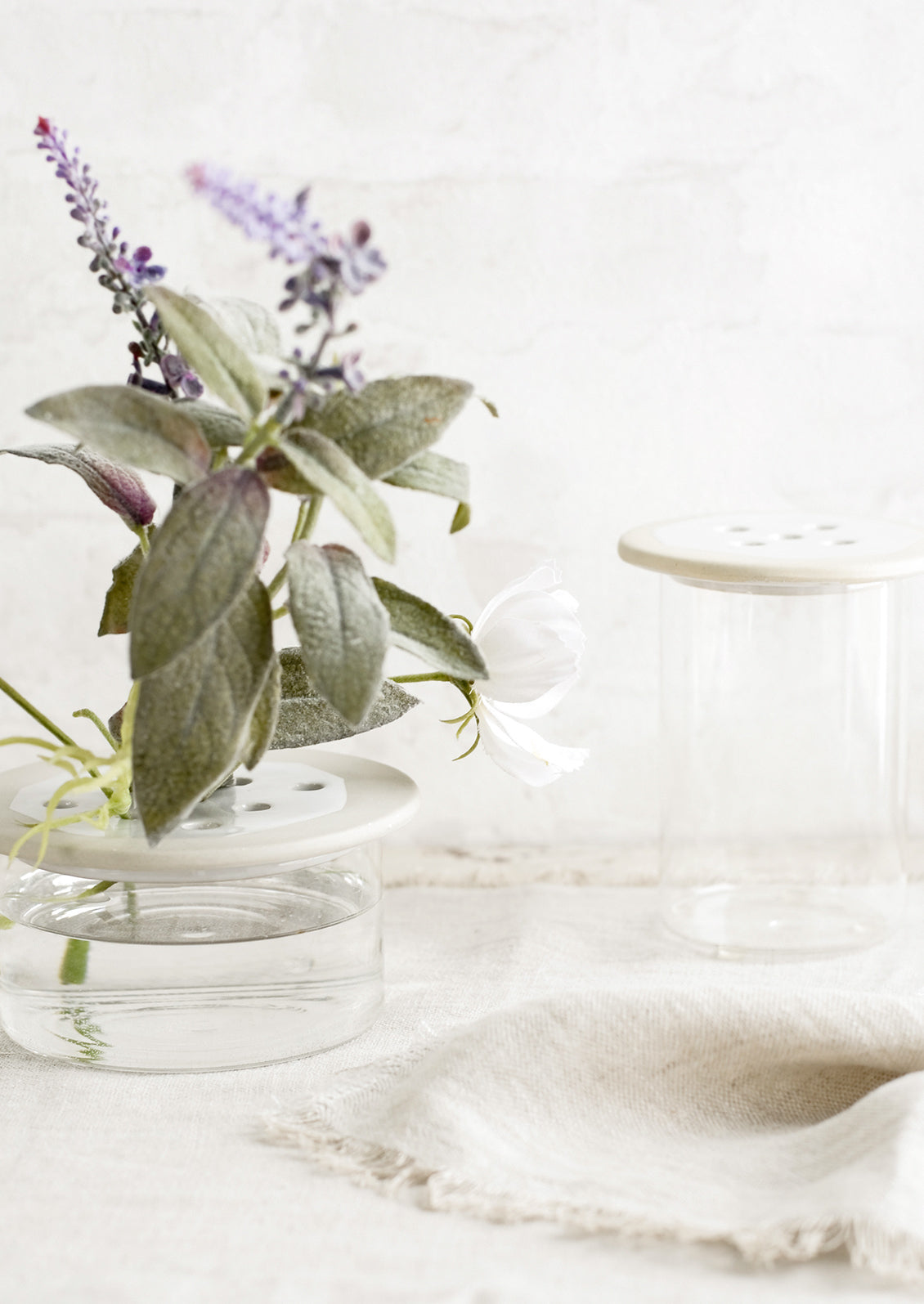 Ceramic and glass flower frogs on a table with water.
