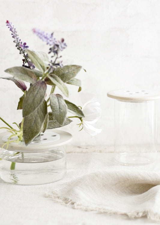 Ceramic and glass flower frogs on a table with water.