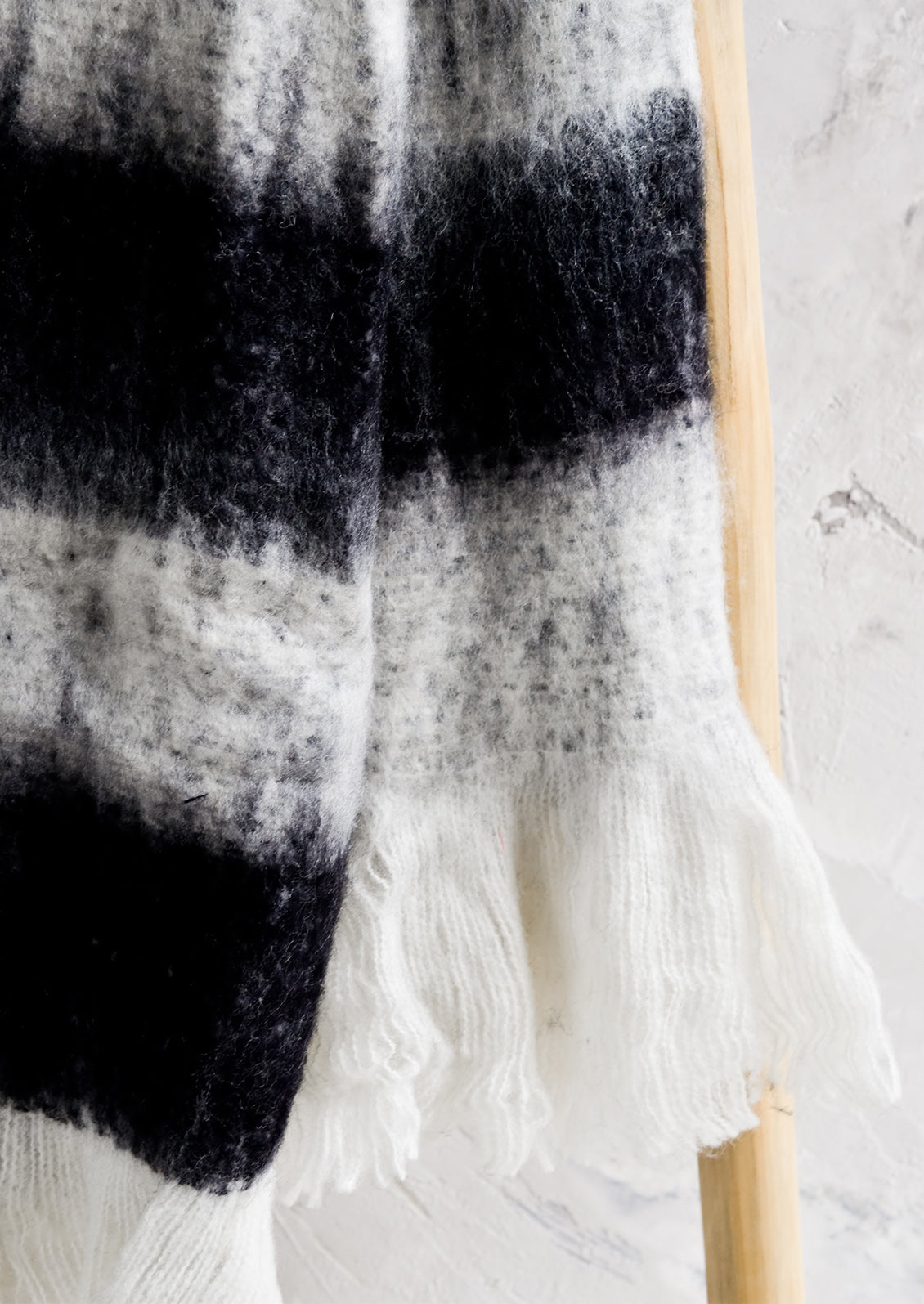A fuzzy black and white throw with white fringe trim.