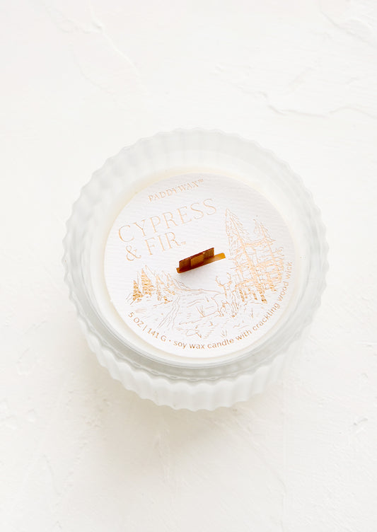 Scented candle in a frosted, fluted glass vessel.