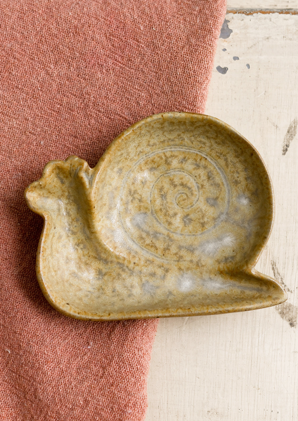 A snail shaped trinket dish in beige.