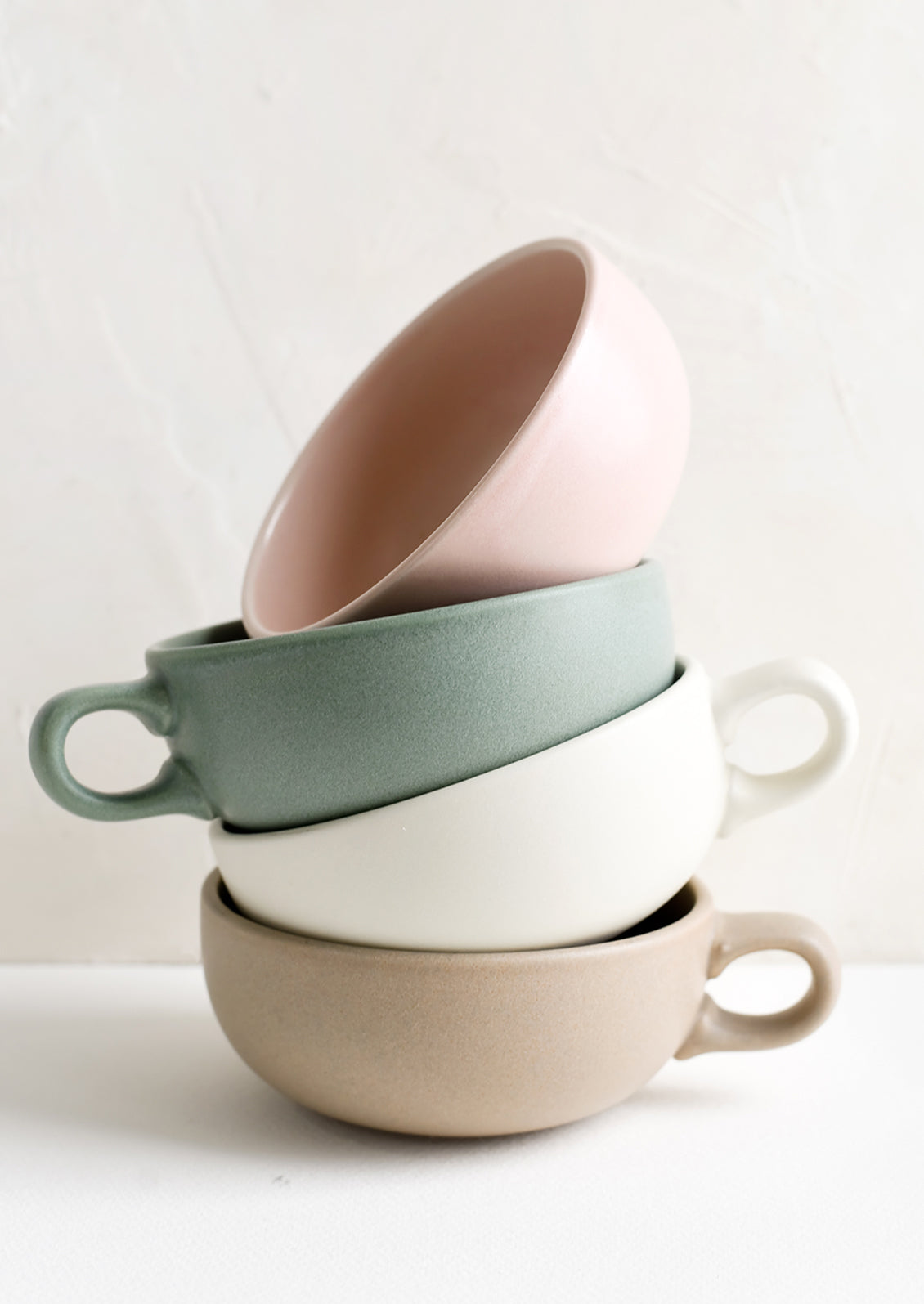 A stacked tower of pastel colored mugs with handles.