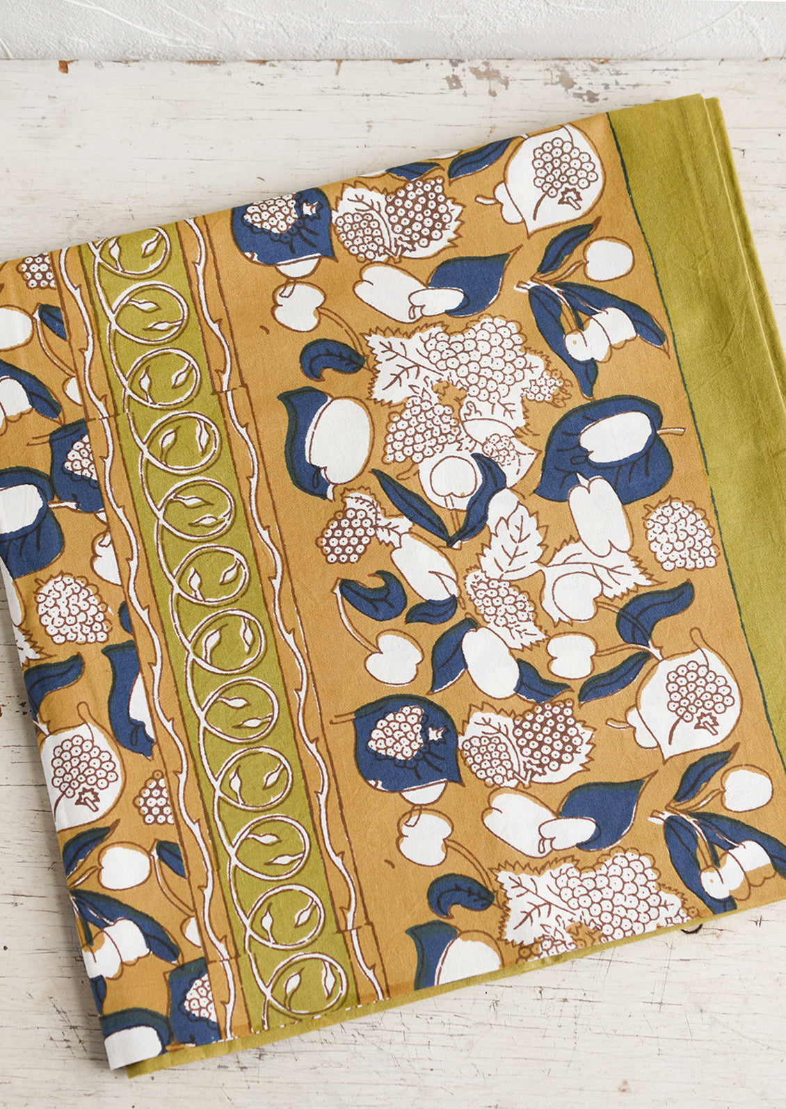 A tablecloth in ochre, navy and chartreuse floral and fruit print.