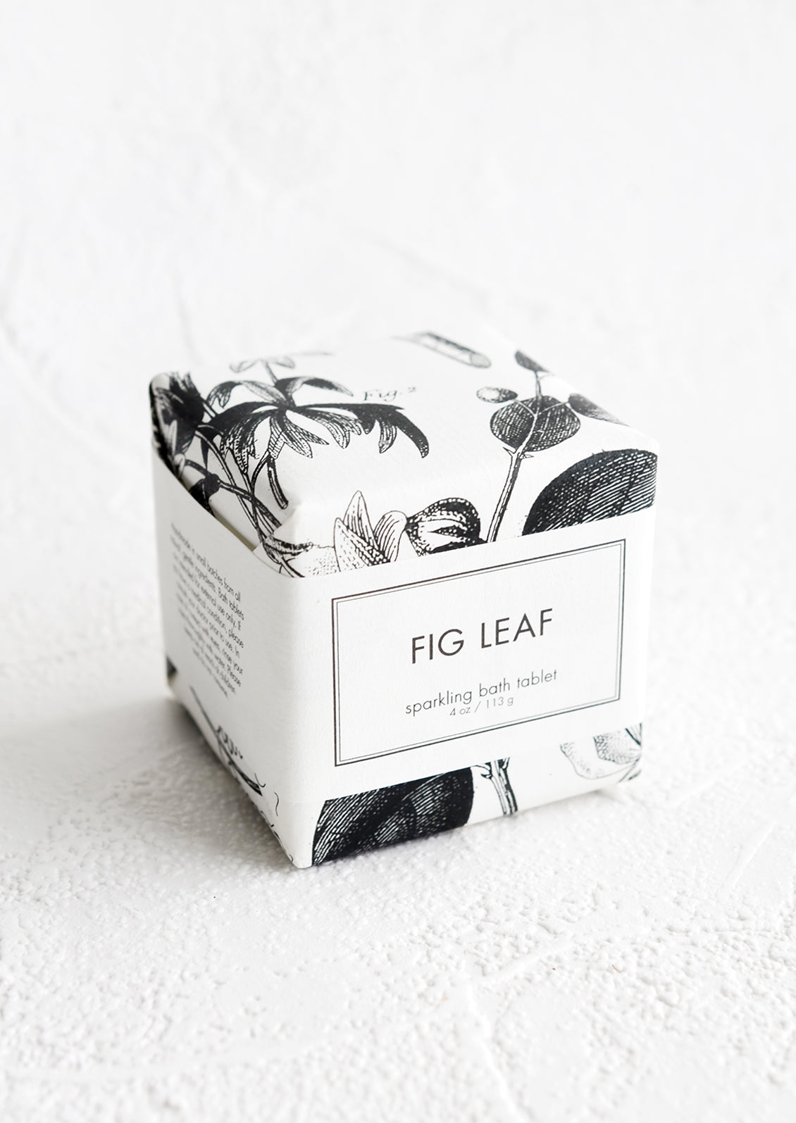 A cube-shaped bath fizzy box with black and white botanical graphic packaging.