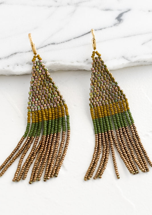 Beaded earrings featuring olive, ochre and brown beads layered into fringe, dangling from a gold hoop.