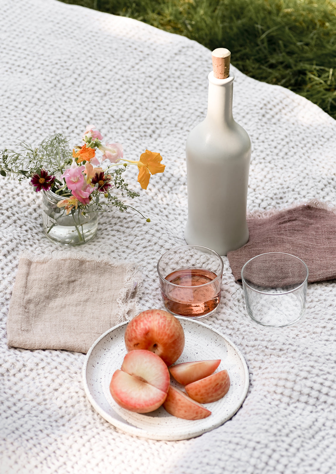 An outdoor dining scene with fruit and wine.