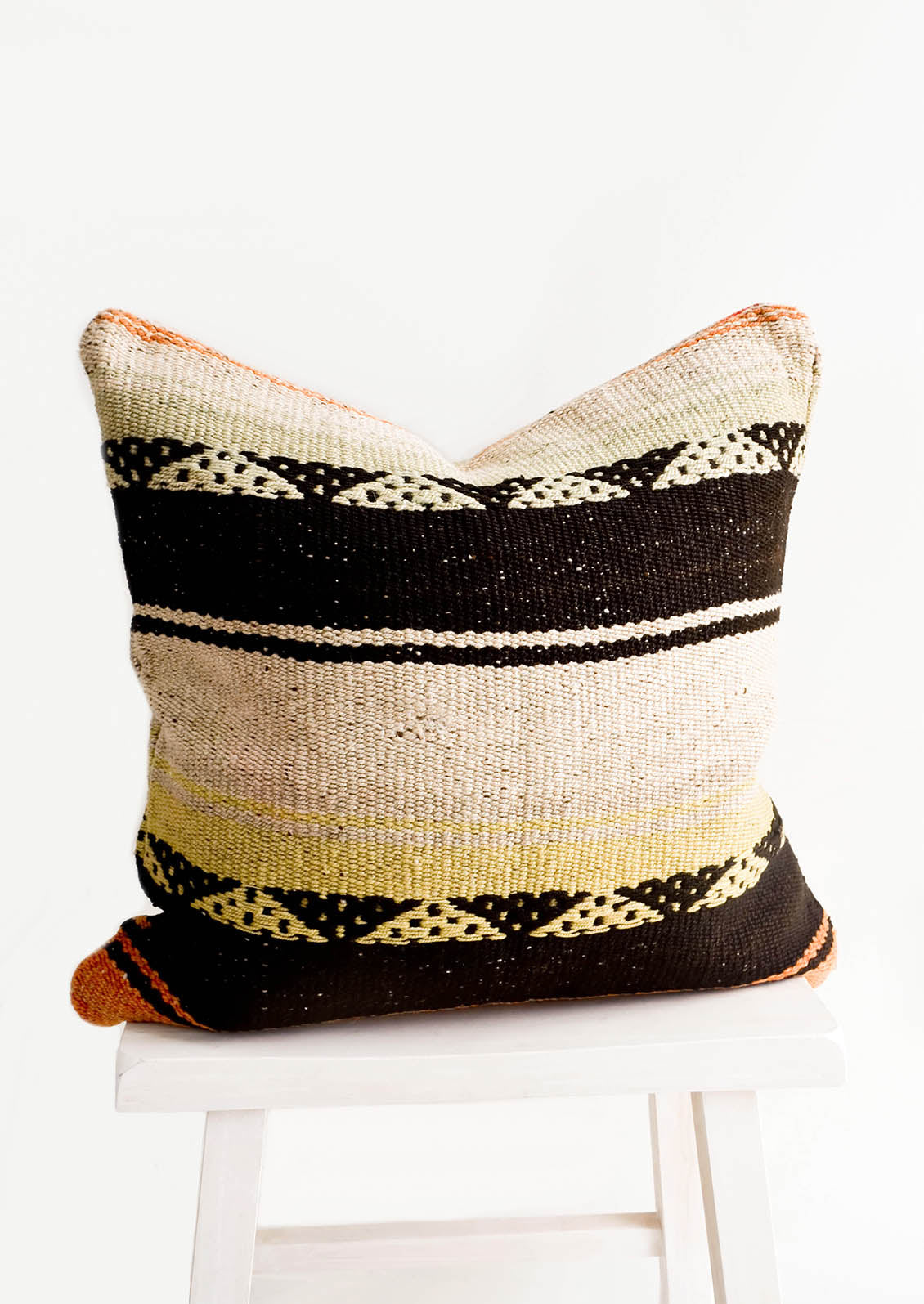 Square throw pillow in wool fabric with tan and black stripes, accents of orange and yellow.