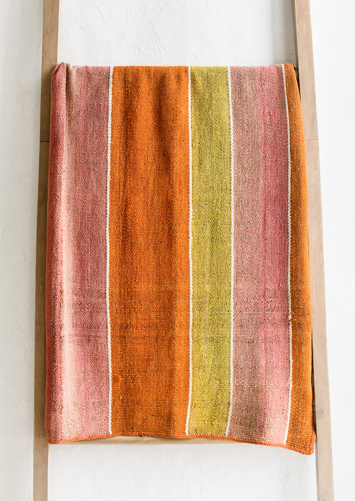 A vintage frazada textile in wide stripe pattern in orange, pink and yellow.