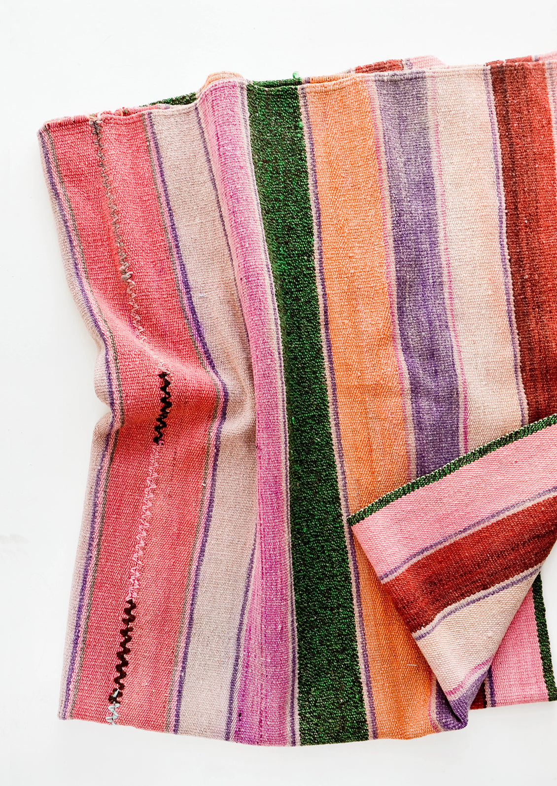 Woven textile intended for use as a rug or blanket, variegated colorful striped pattern.