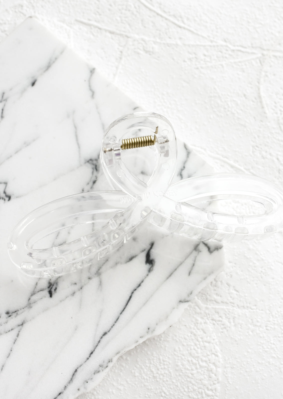 A curvy hair clip with knotted loop design in clear.