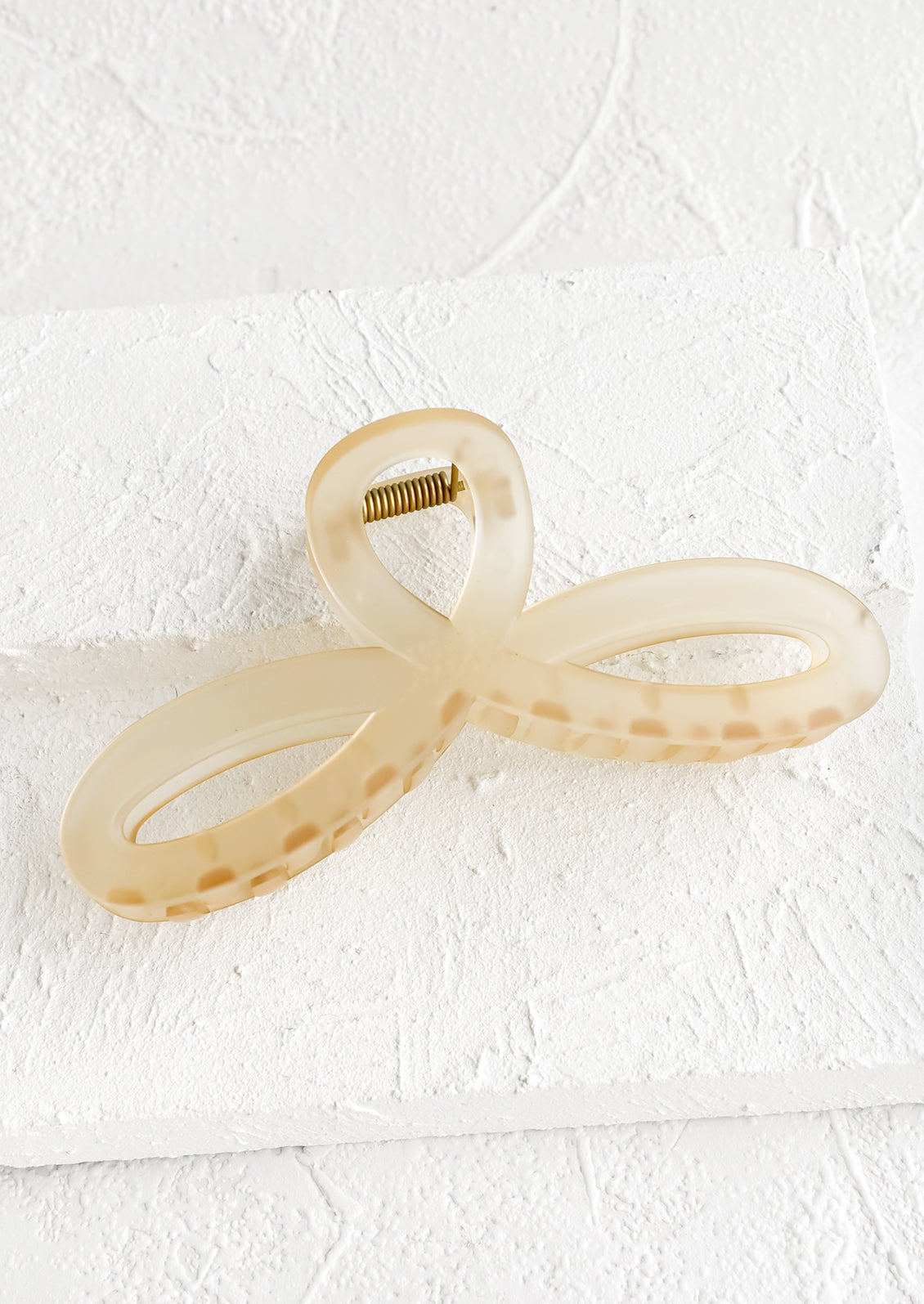 A curvy hair clip with knotted loop design in frosted tan.