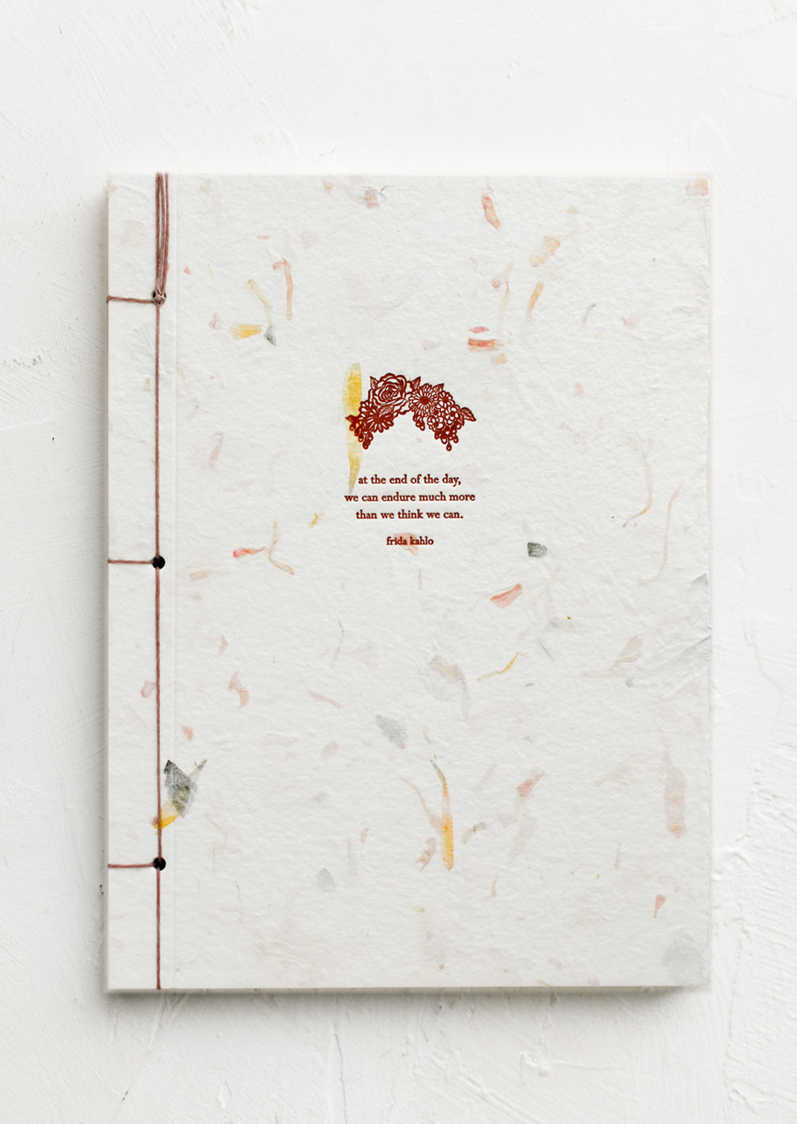 A journal with flower paper cover with Frida Khalo quote.