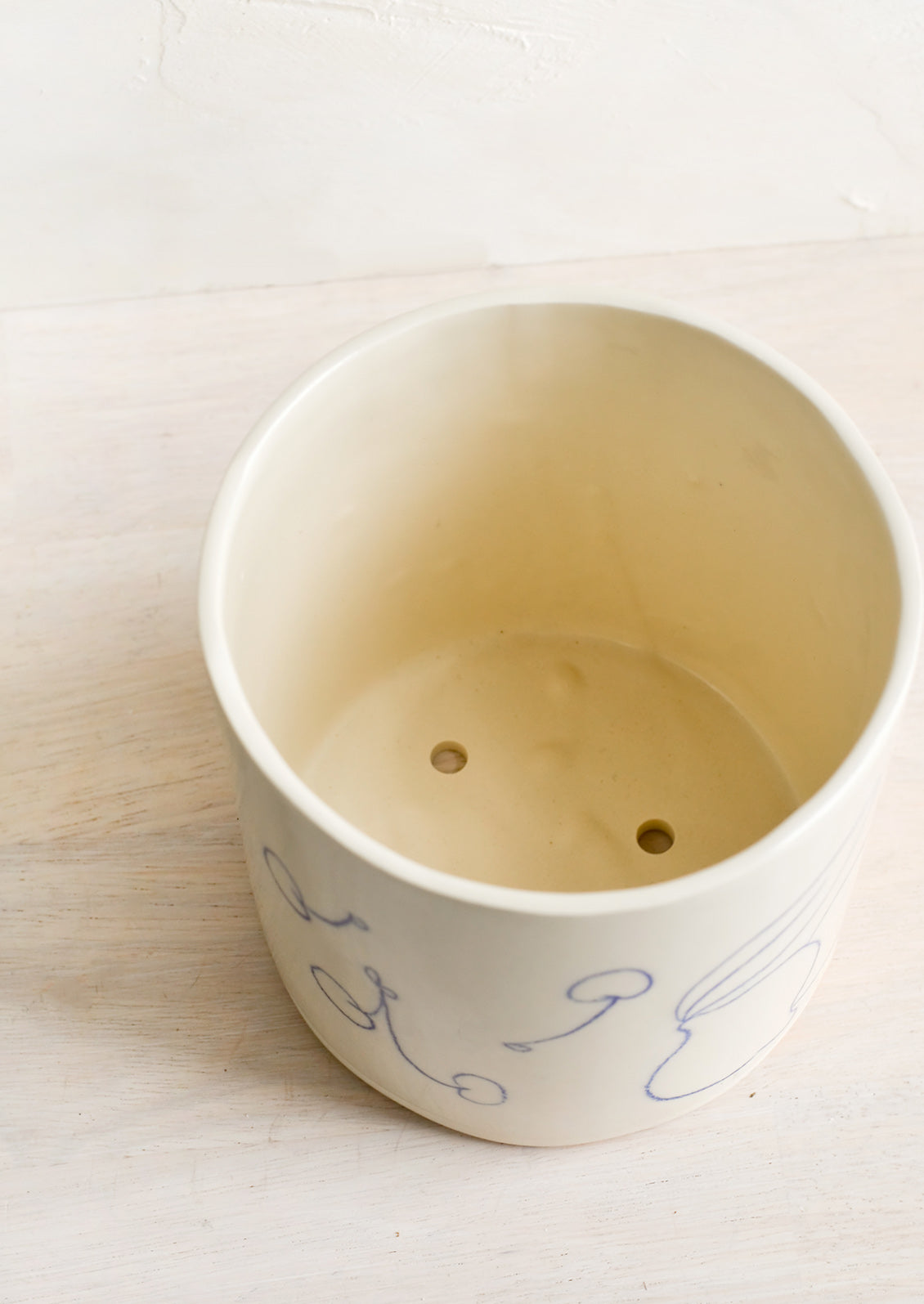 A ceramic planter with drainage holes at bottom.