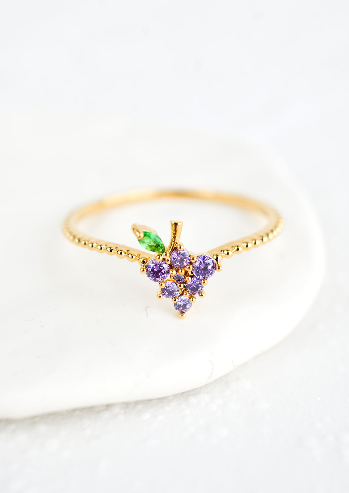 A gold ring with beaded texture and grape shaped crystal front.
