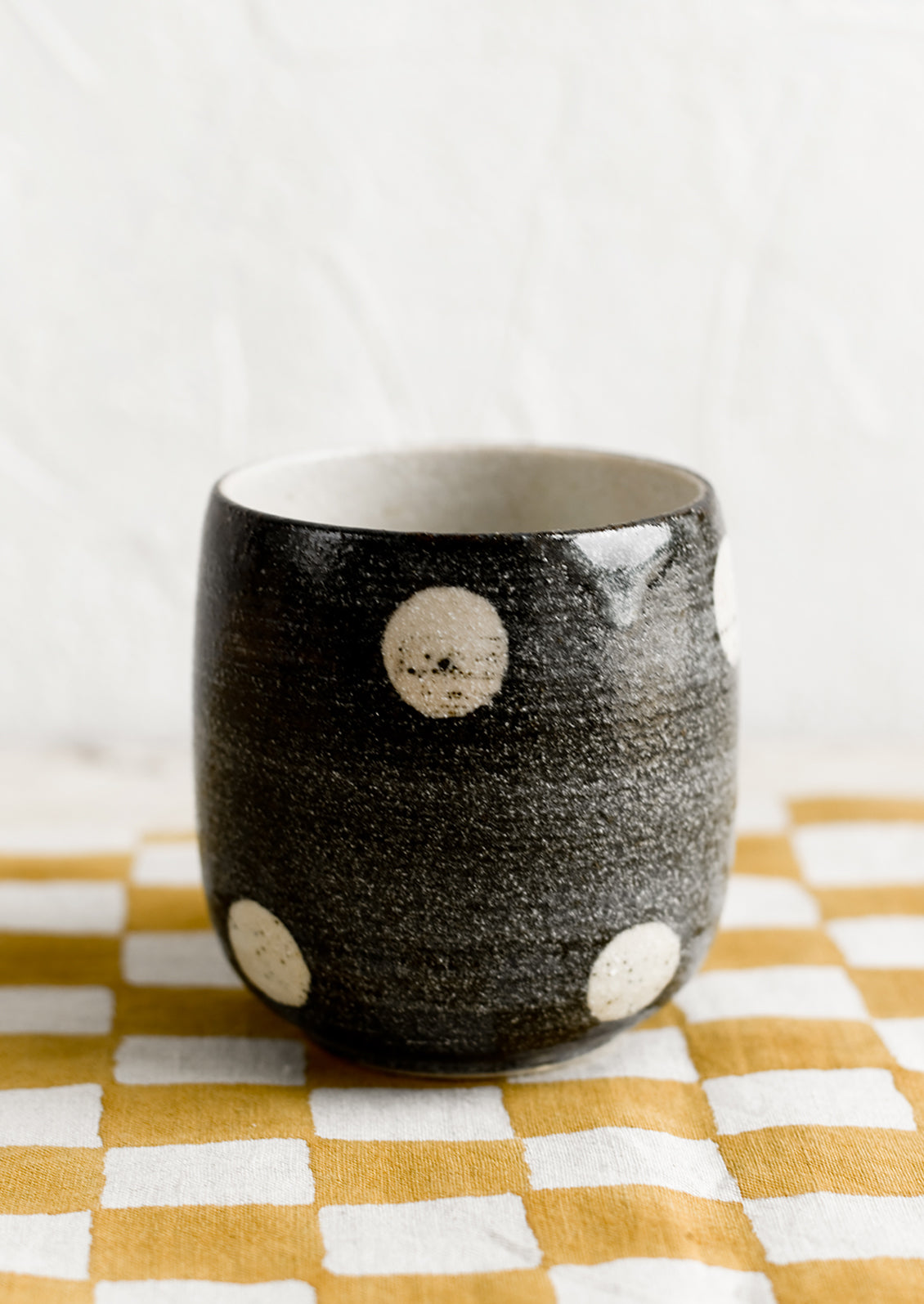 A black ceramic cup with white polka dots.
