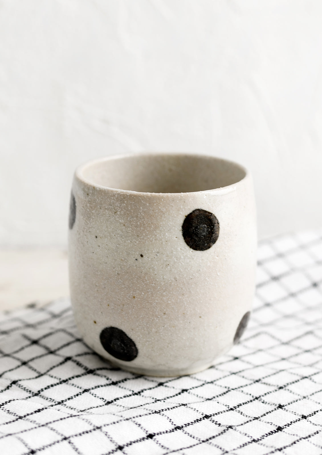 A white ceramic cup with black polka dots.