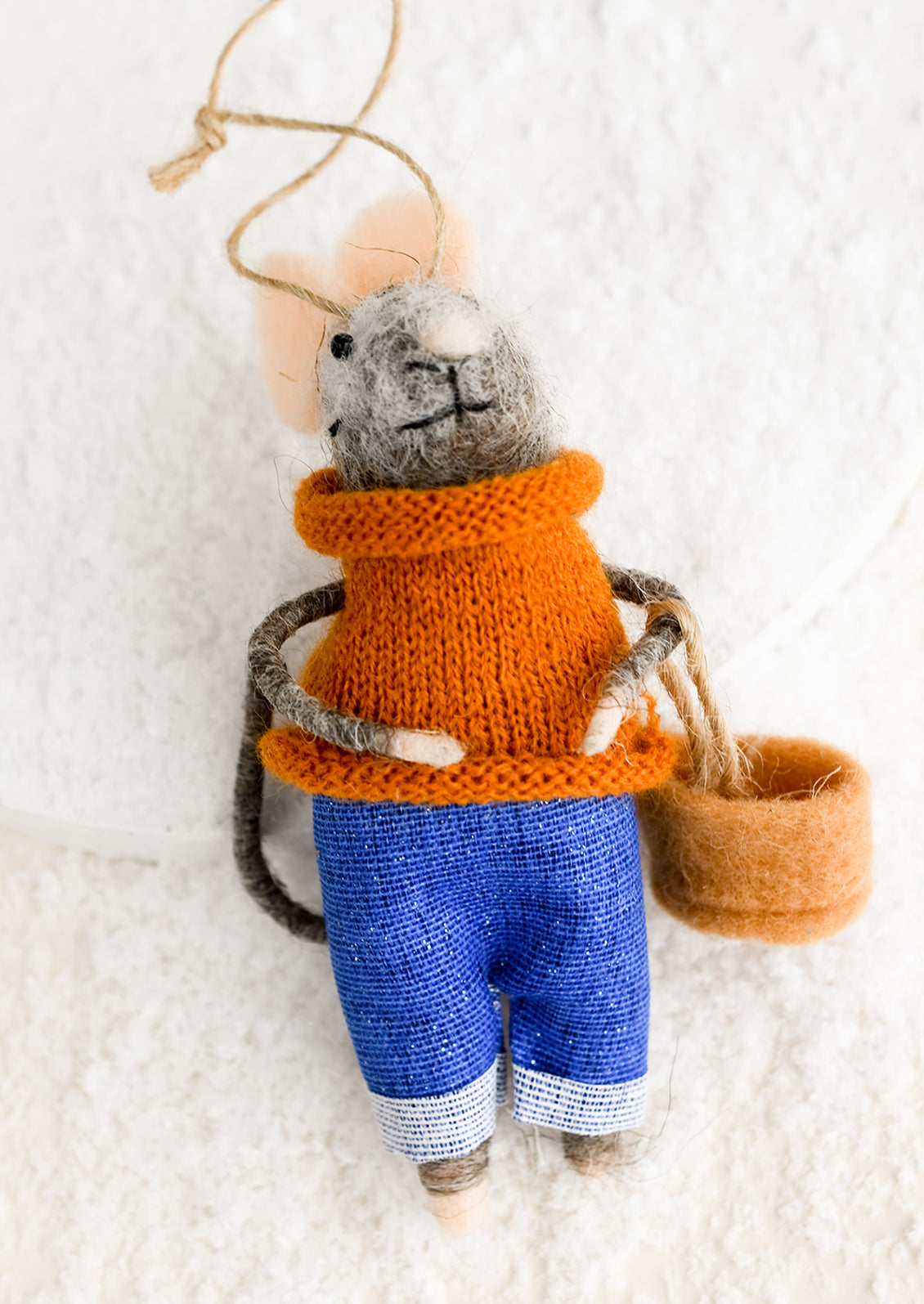 A felted mouse ornament wearing a sweater and holding a basket.