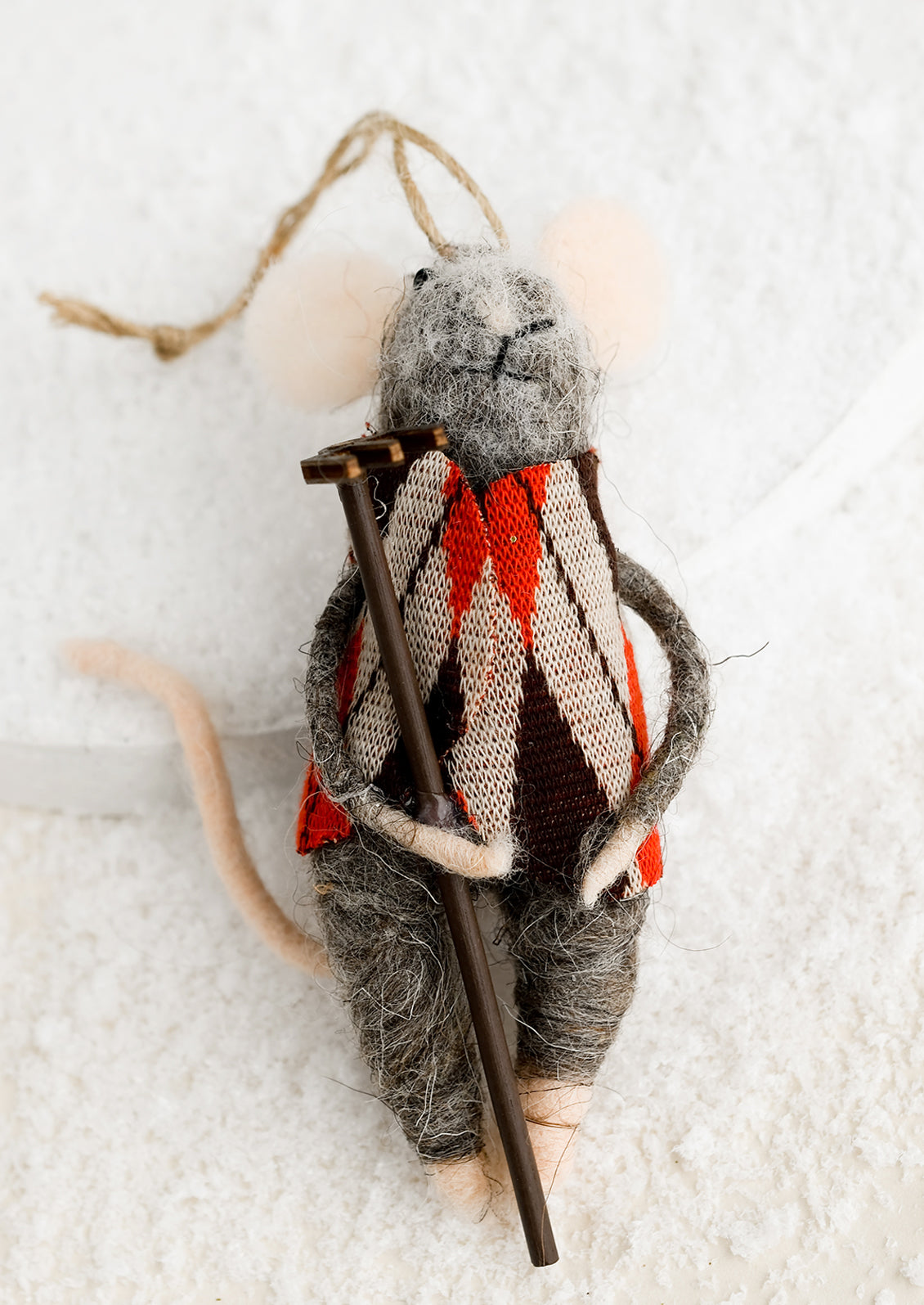 A felted mouse ornament wearing an argyle sweater and holding a rake.