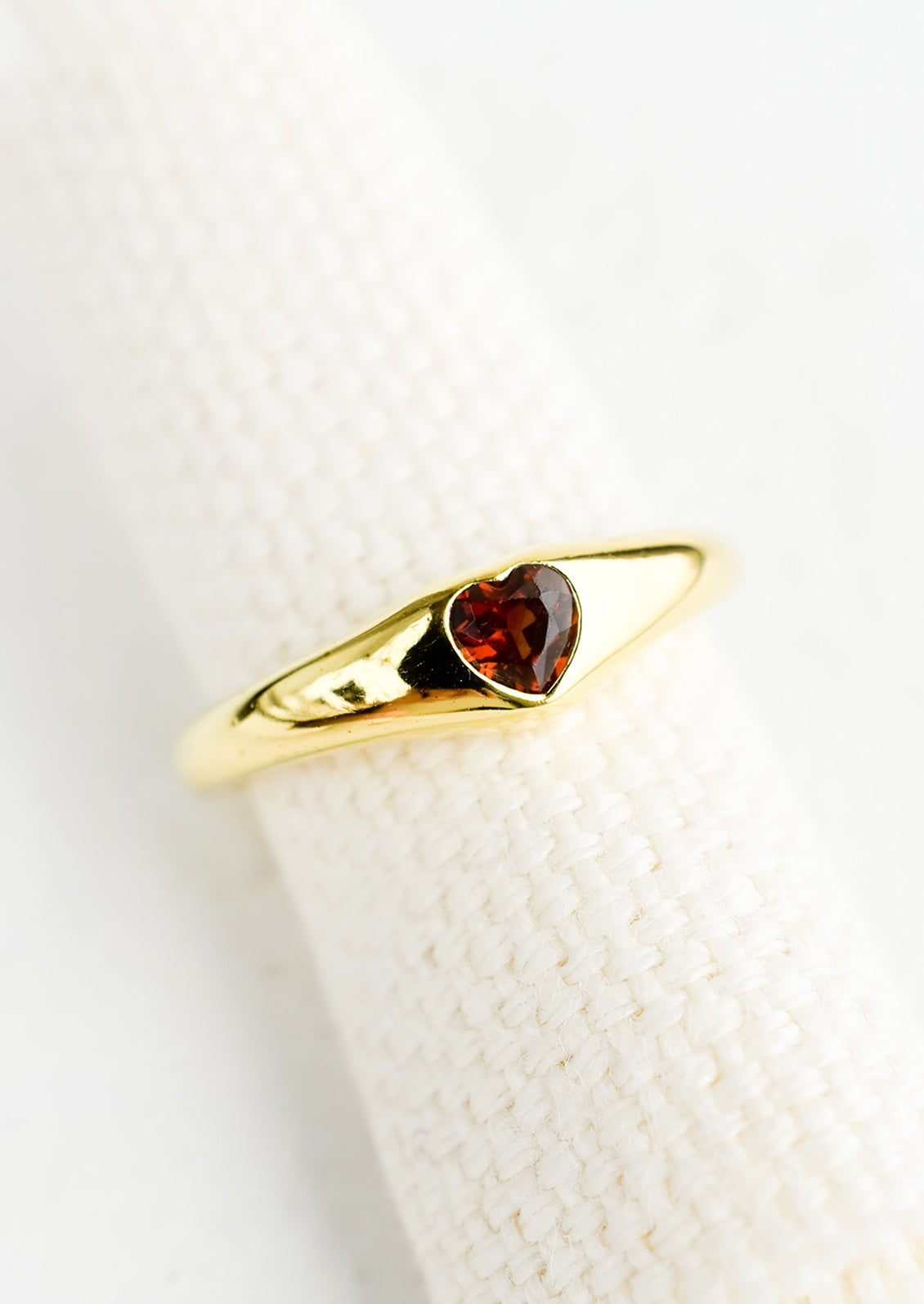 An adjustable gold ring with heart shaped garnet stone.