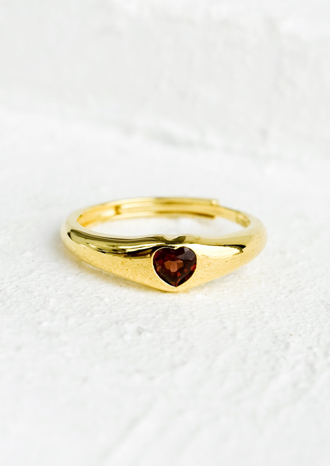 An adjustable gold ring with heart shaped garnet stone.