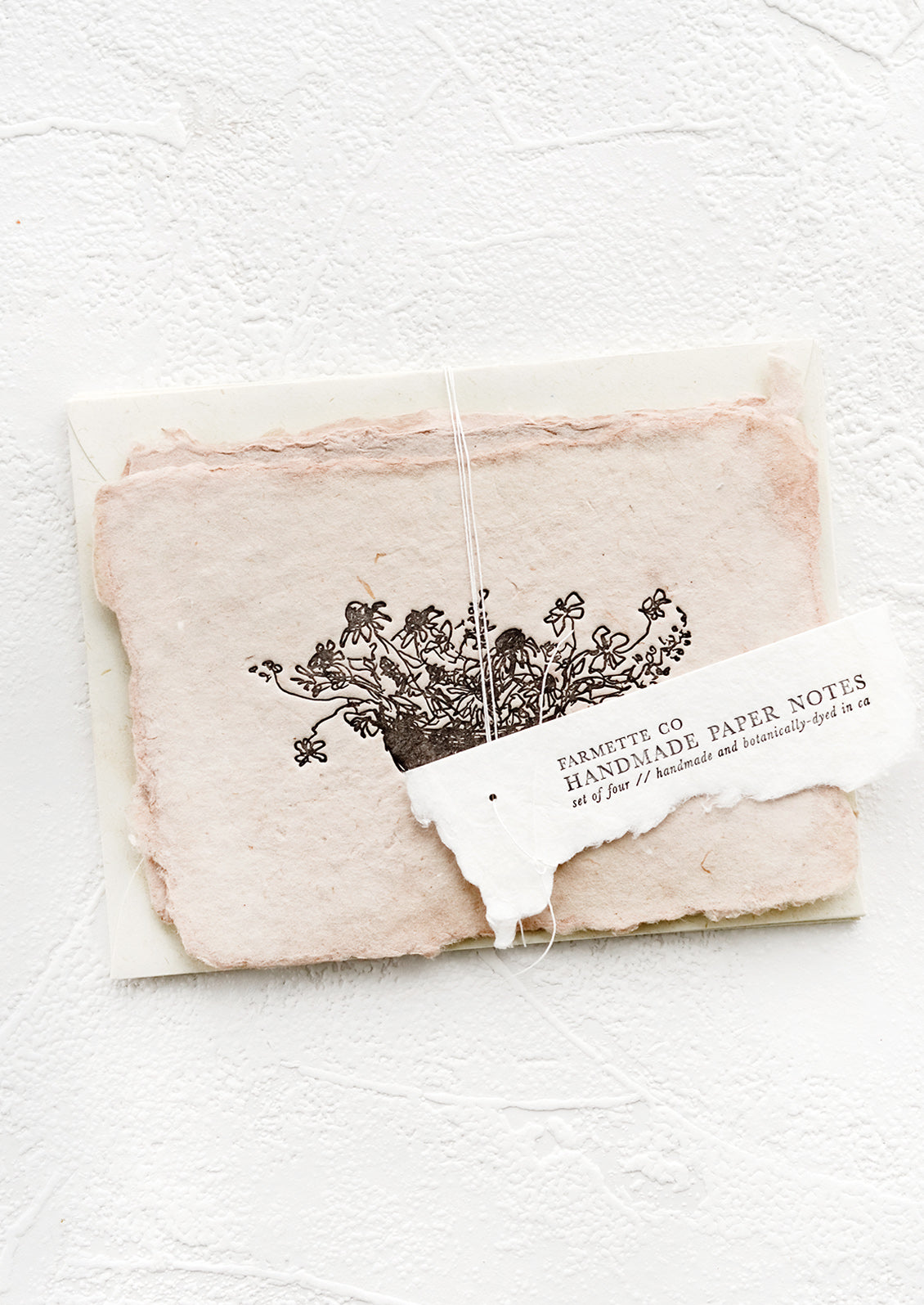 A packaged set of cards made from handmade paper with a letterpress printed image of flowers in a bowl.