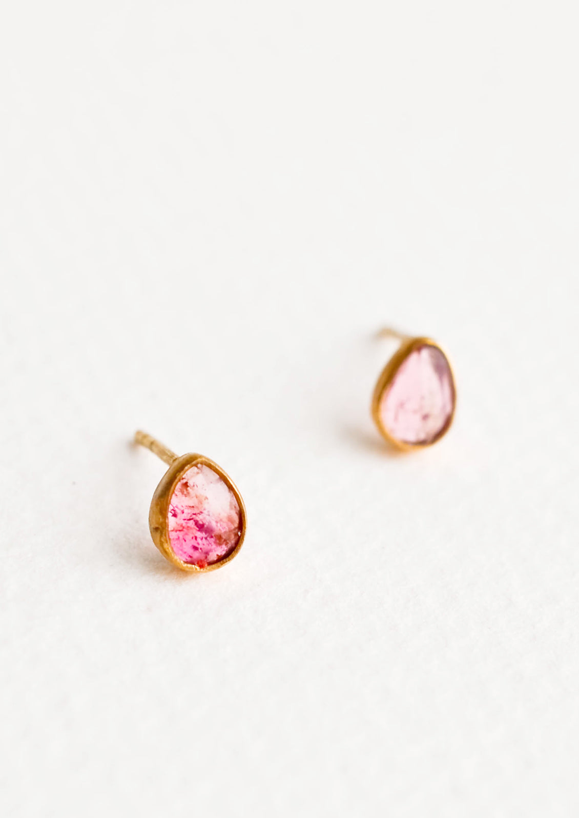 Brass asymmetric stud earrings featuring a pink multicolored tourmaline stone.