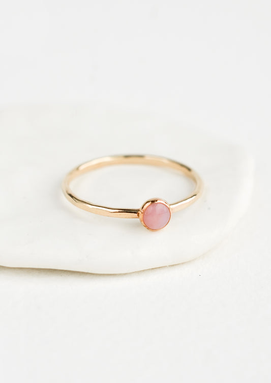 Thin gold ring with bezel set pink stone.