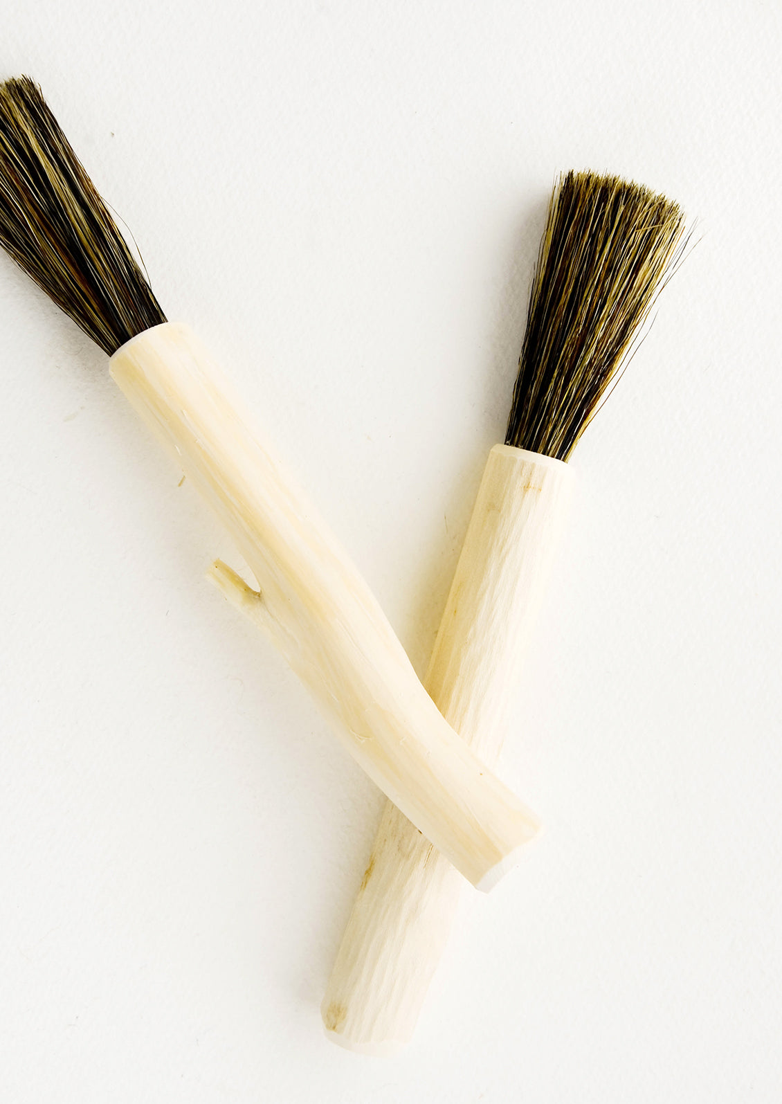 Hard-carved wooden brush in long and skinny shape with bristle end