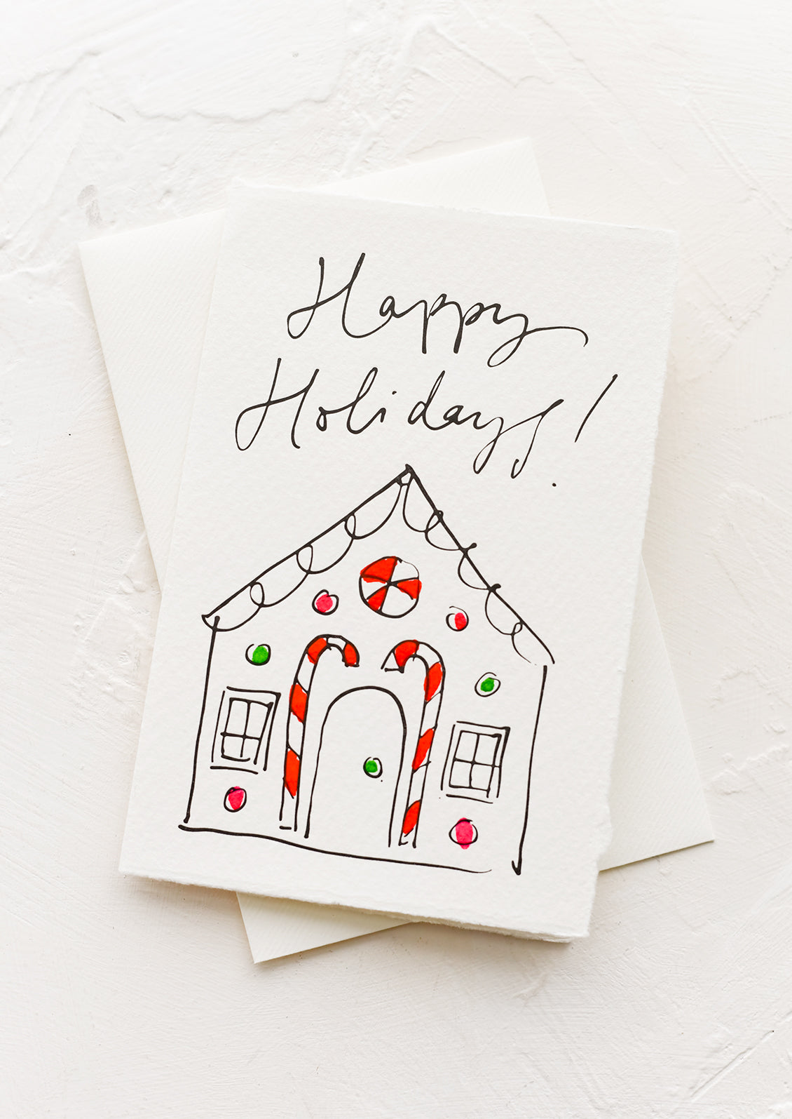 A greeting card with illustration of gingerbread house, text reads "Happy holidays!".