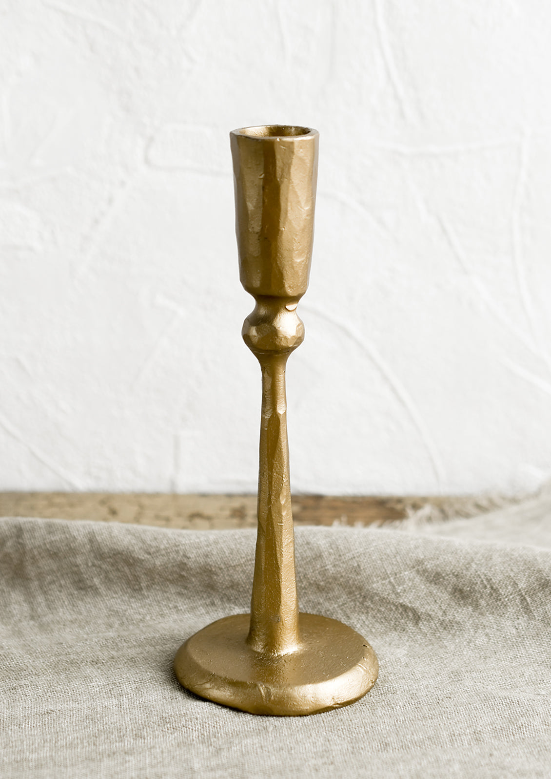 A tall candlestick holder in gold finish cast iron.