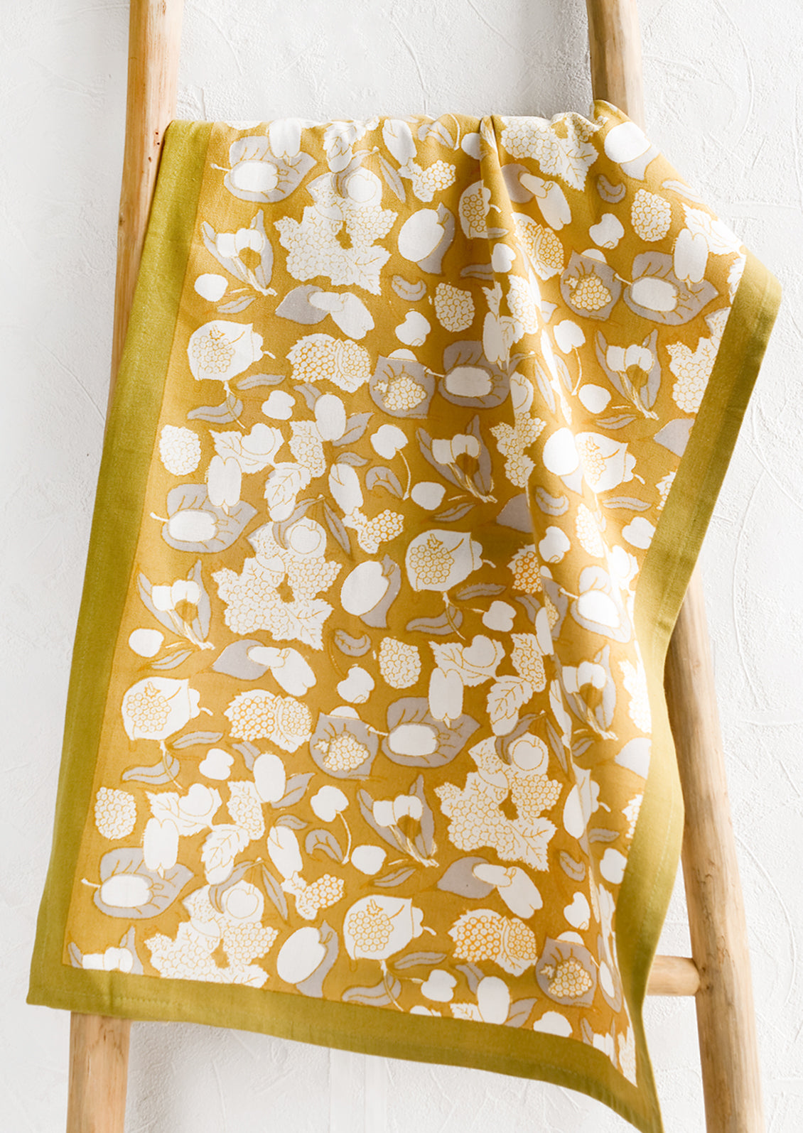 A gold, grey and white fruit print tea towel.
