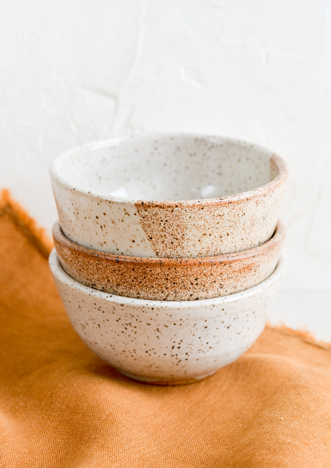 A stack of three small speckled ceramic bowls.