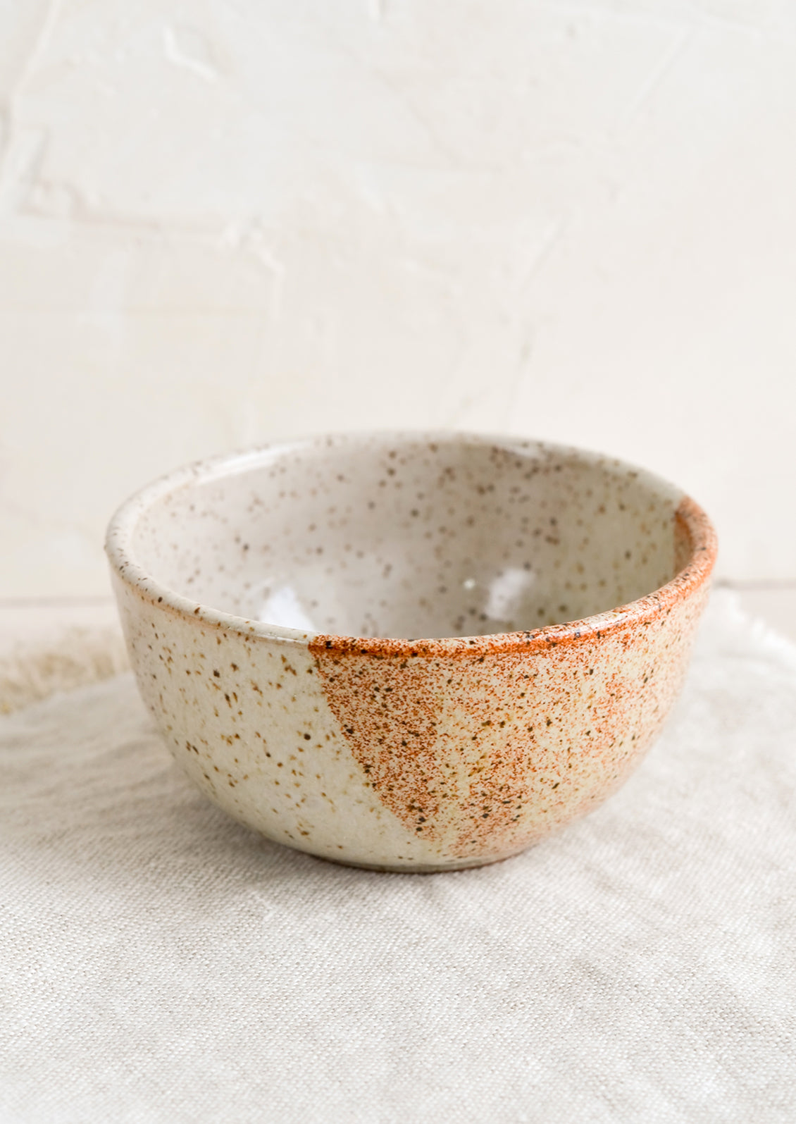 A small ceramic bowl in half & half speckled white and rust.