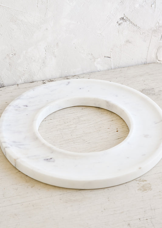 A circular white marble tray with an empty center.