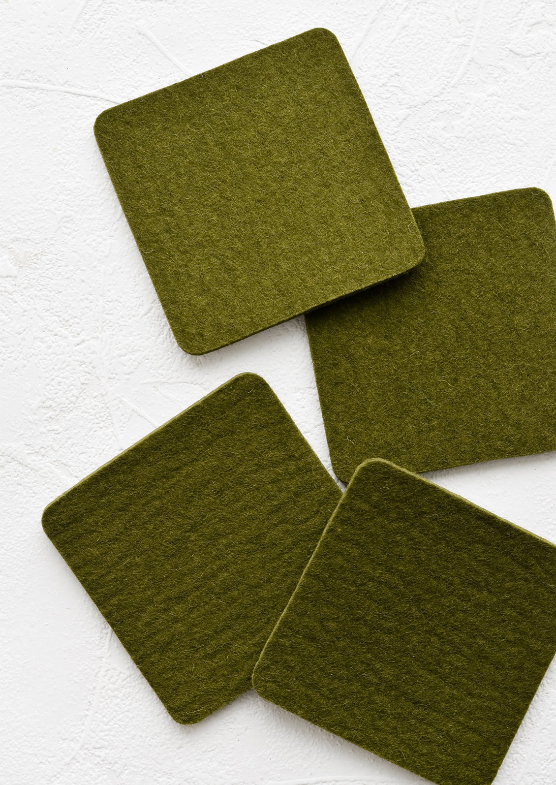 A set of four square merino wool coasters in army green.