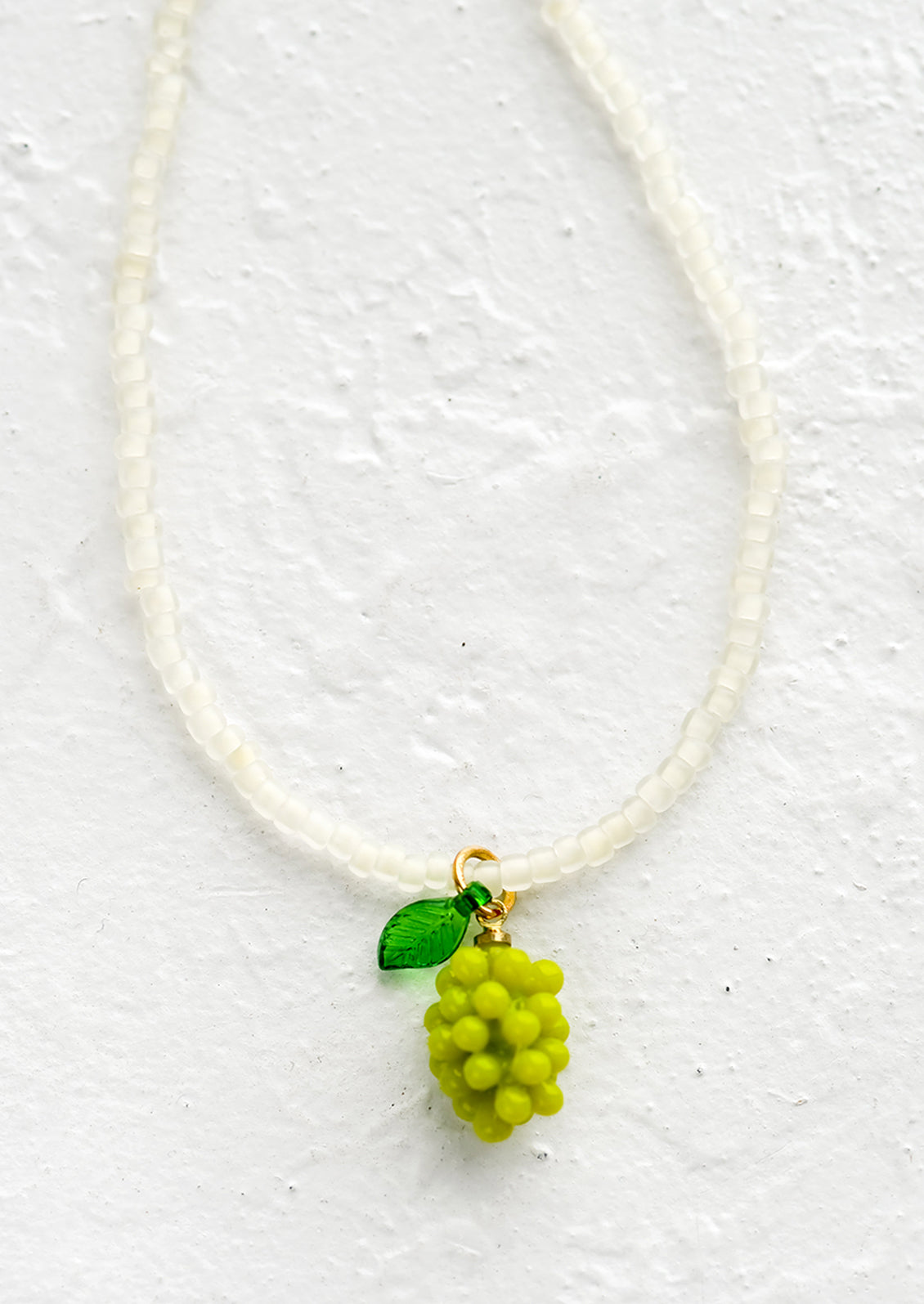 A beaded necklace with green grape bunch charm.