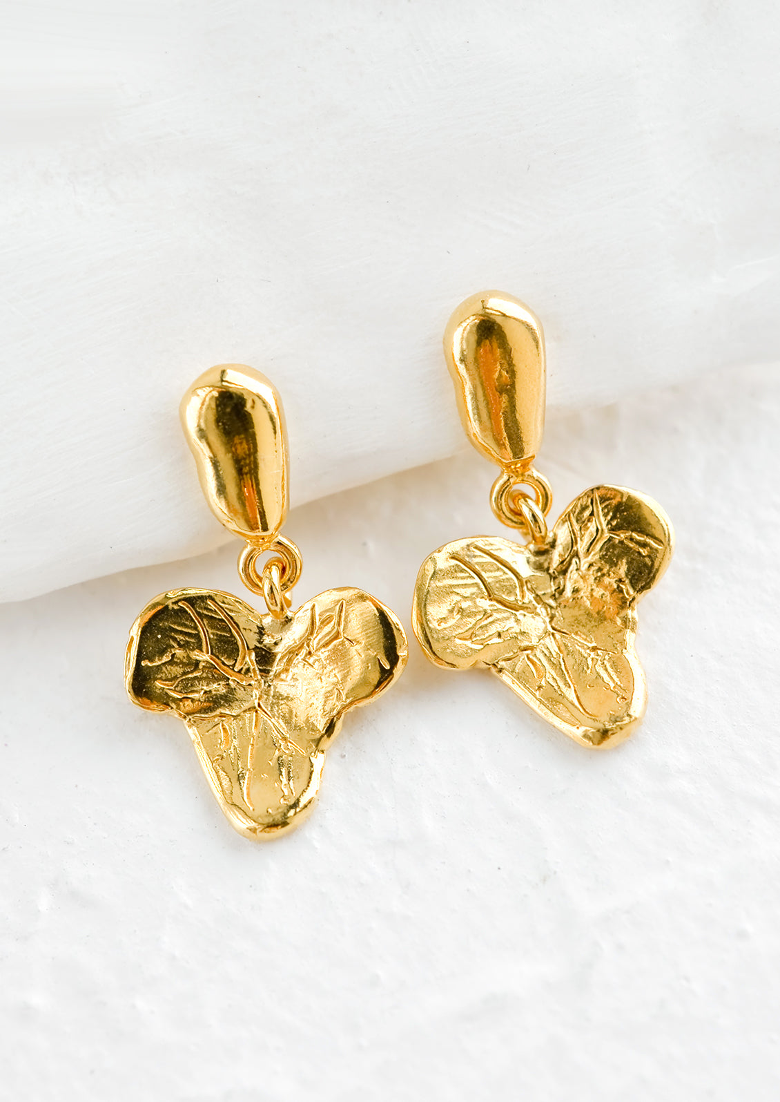 A pair of gold post back earrings in grape leaf shape.