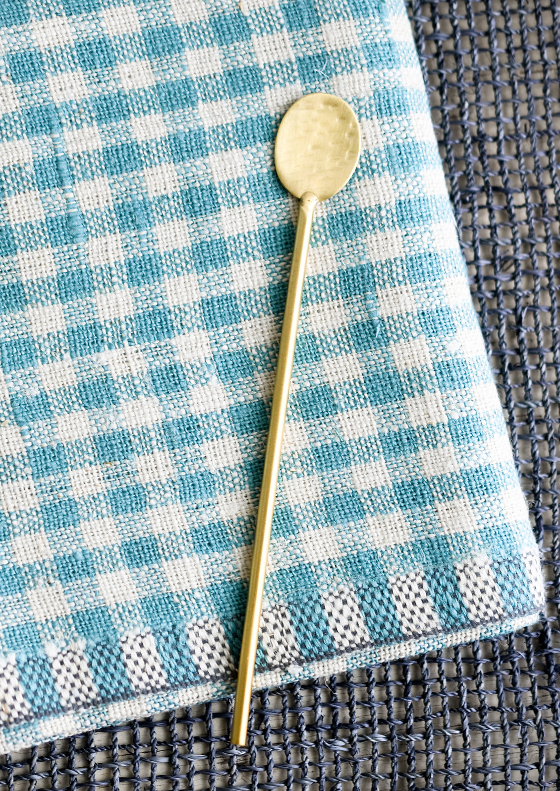 A long, skinny hammered gold spoon with slim, round handle.
