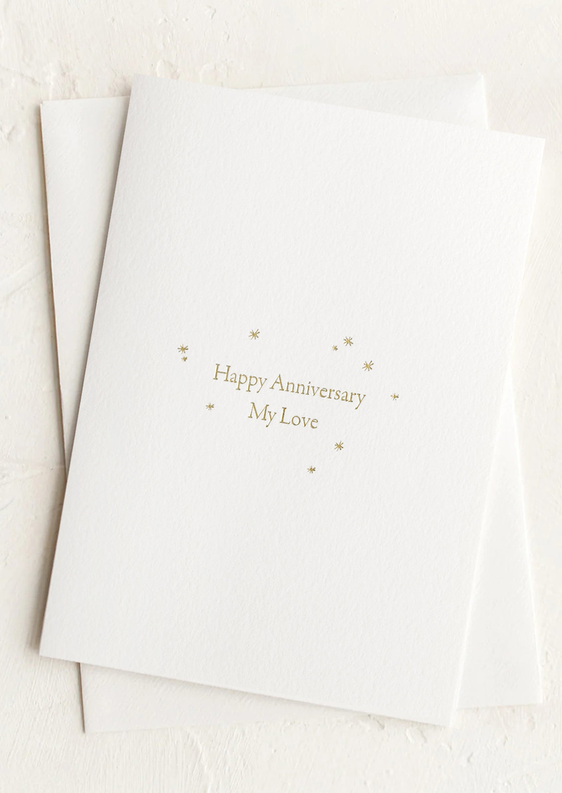 A card with gold text and stars reading "Happy Anniversary My Love".