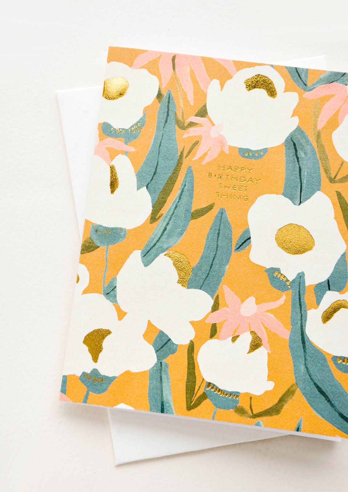 Greeting card with flowers on mustard colored background, small golden lettering reads "Happy Birthday Sweet Thing"
