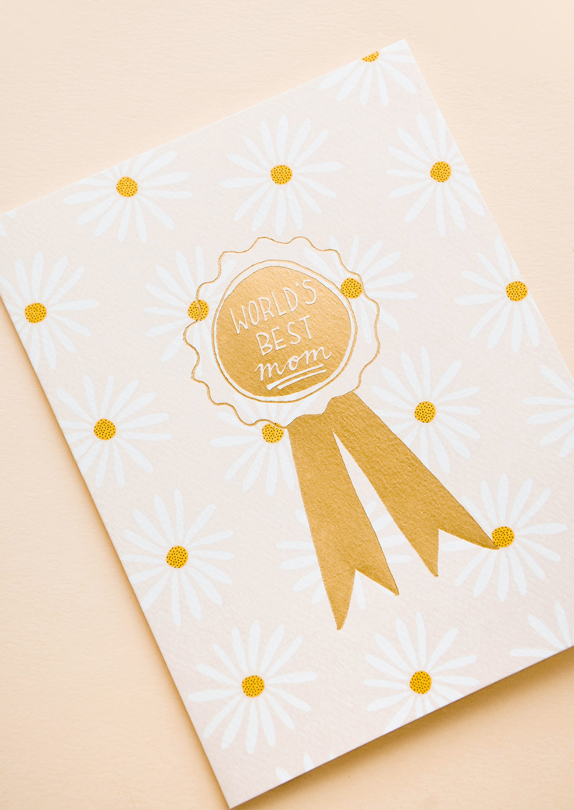 Greeting card with allover daisy pattern and gold ribbon reading "World's Best Mom" 